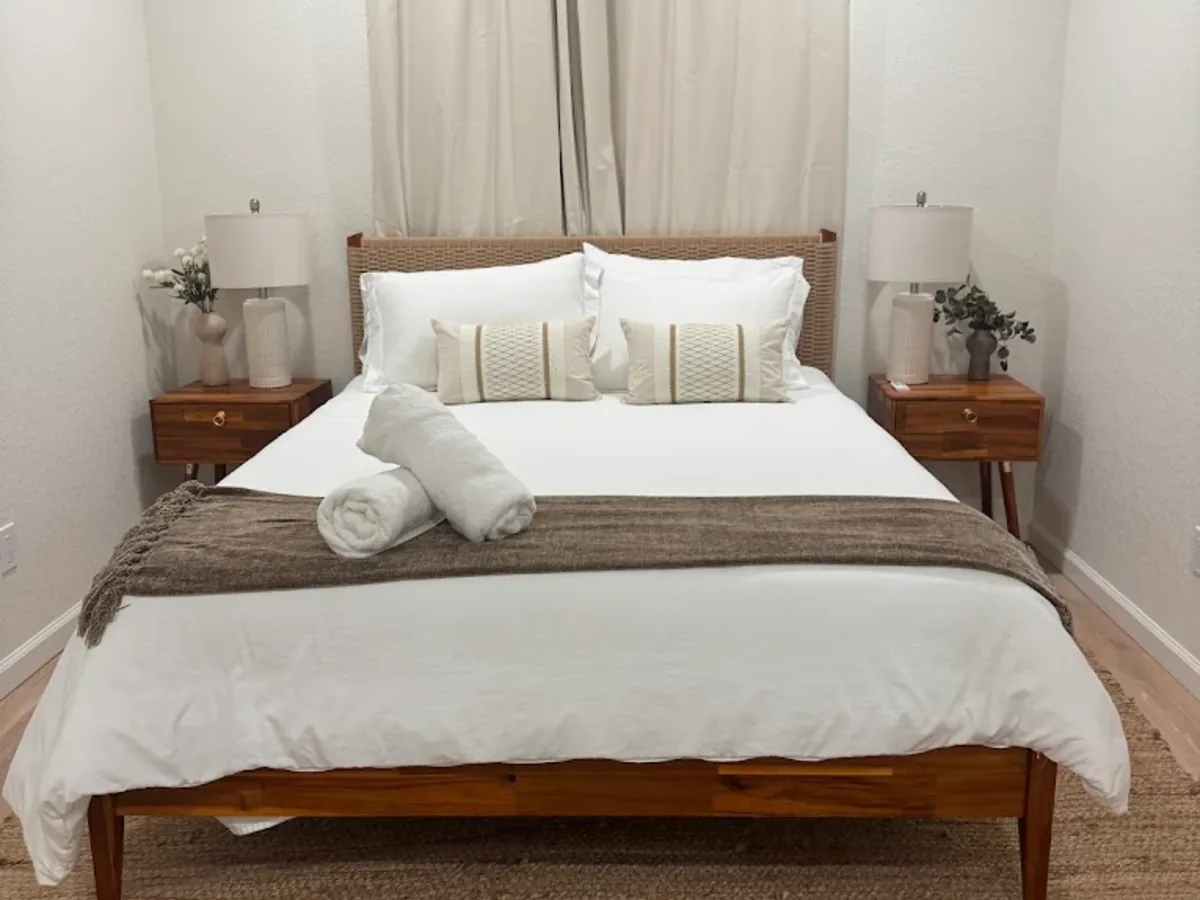 Bed made with white linens and rolled towels